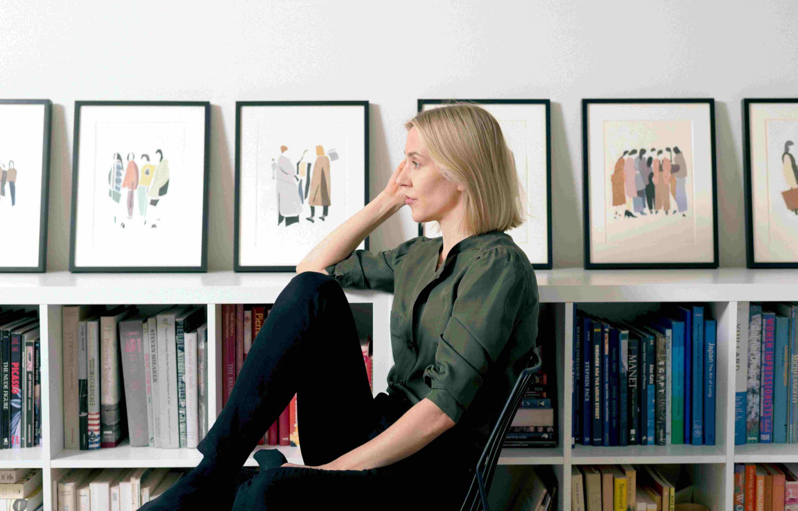 A woman sitting near artworks and books